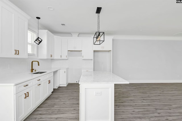 kitchen featuring a kitchen island, sink, pendant lighting, and white cabinets