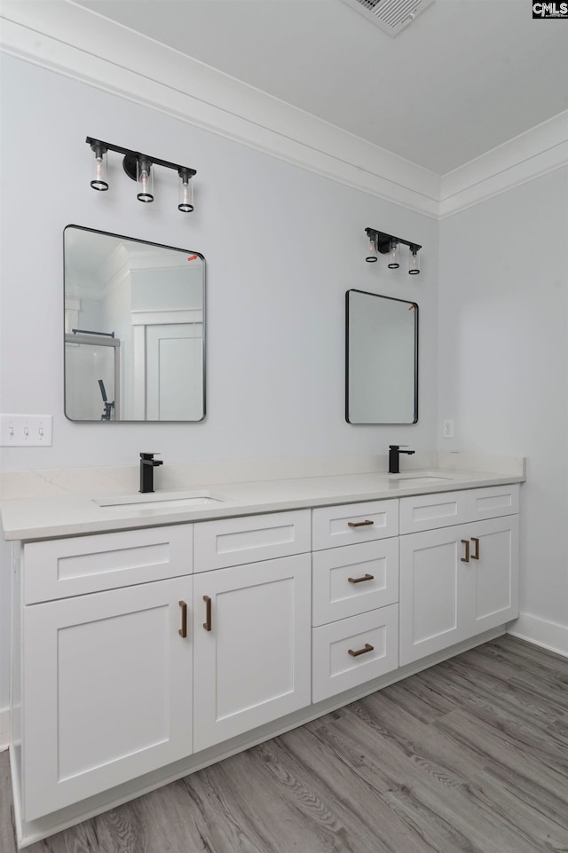 bathroom with vanity, hardwood / wood-style flooring, ornamental molding, and walk in shower