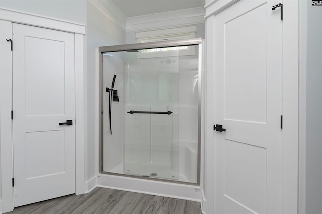 bathroom with hardwood / wood-style flooring, crown molding, and an enclosed shower