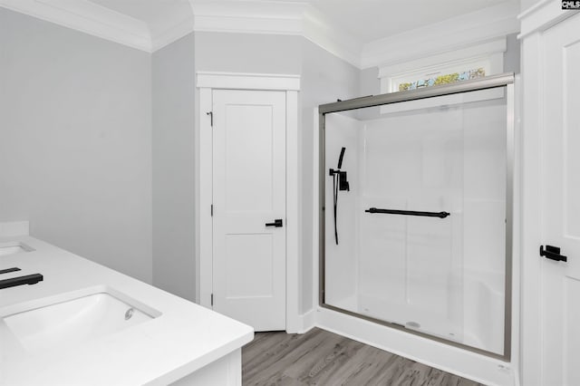 bathroom featuring ornamental molding, wood-type flooring, an enclosed shower, and vanity