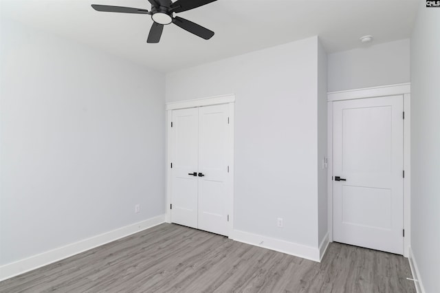 unfurnished bedroom with light wood-type flooring, ceiling fan, and a closet