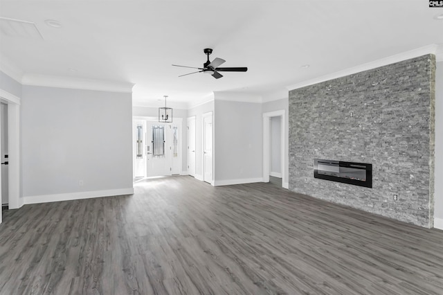 unfurnished living room featuring ceiling fan, ornamental molding, a stone fireplace, and dark hardwood / wood-style flooring