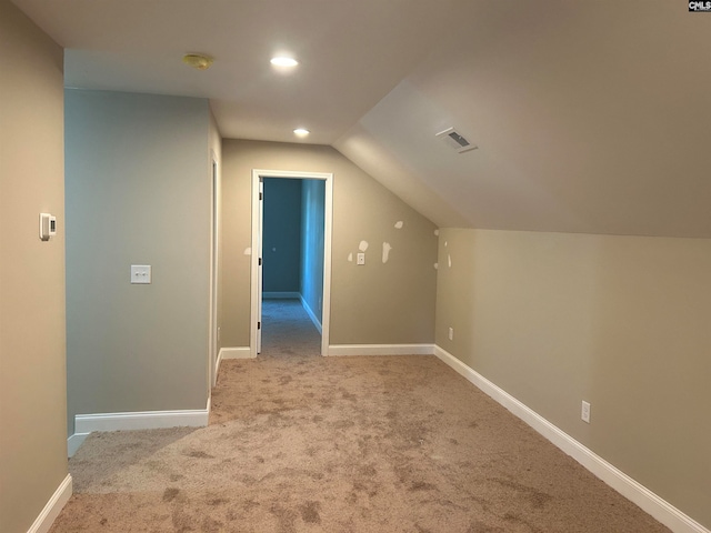 bonus room with lofted ceiling and light carpet