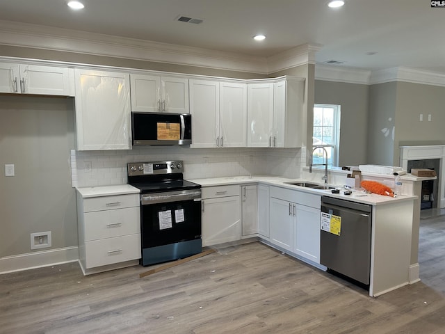 2107 Durham Dr, West Columbia, SC 29170 - kitchen featuring appliances with stainless steel finishes, light wood-style floors, light countertops, a peninsula, and decorative backsplash