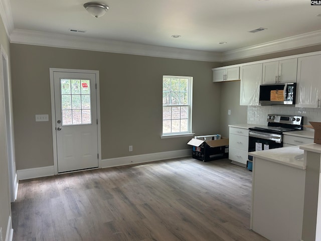 kitchen with light hardwood / wood-style flooring, ornamental molding, appliances with stainless steel finishes, tasteful backsplash, and white cabinetry