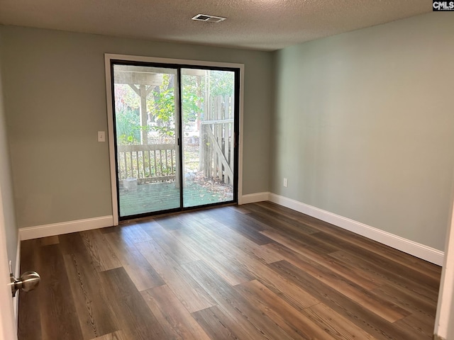 spare room featuring dark hardwood / wood-style flooring and a textured ceiling