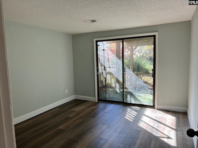 empty room with dark hardwood / wood-style flooring and a textured ceiling