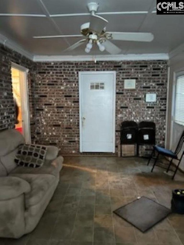 living room featuring ceiling fan and brick wall