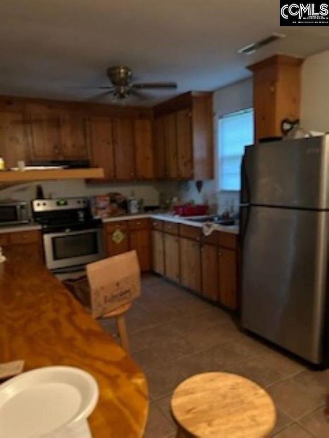 kitchen featuring white range with electric cooktop, stainless steel refrigerator, ceiling fan, and light tile patterned flooring