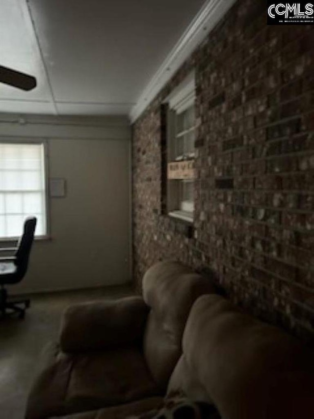 interior space with crown molding, ceiling fan, and brick wall