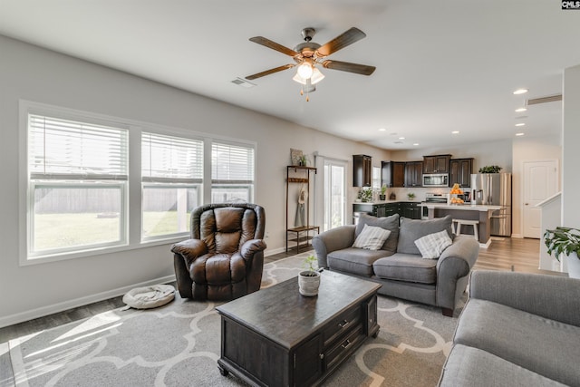 living room with ceiling fan and light hardwood / wood-style flooring