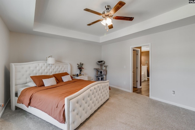 carpeted bedroom with a tray ceiling and ceiling fan