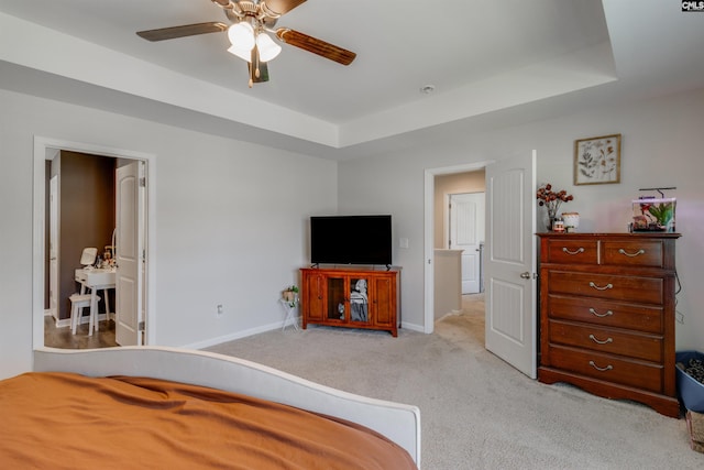 bedroom featuring light carpet, a tray ceiling, and ceiling fan