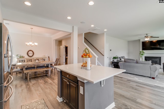 kitchen featuring light wood-type flooring, pendant lighting, a breakfast bar area, a kitchen island, and stainless steel refrigerator