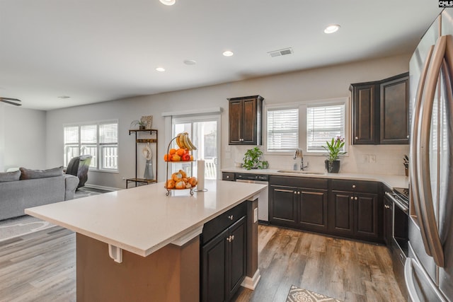 kitchen featuring sink, decorative backsplash, light wood-type flooring, appliances with stainless steel finishes, and a kitchen island