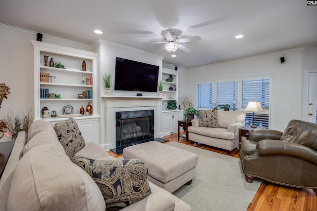 living room featuring hardwood / wood-style flooring, crown molding, and a premium fireplace