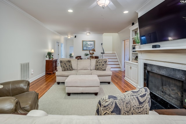 living room featuring light hardwood / wood-style flooring, ornamental molding, and a premium fireplace