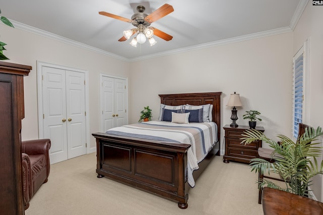 bedroom with crown molding, light colored carpet, ceiling fan, and two closets