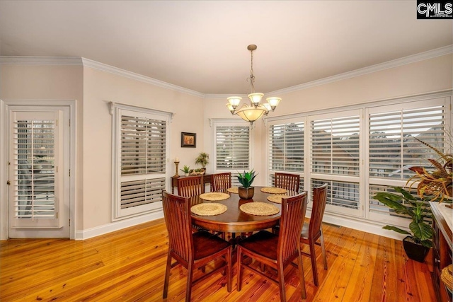 dining space with crown molding, an inviting chandelier, and light hardwood / wood-style floors