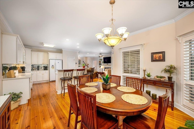 dining space featuring ornamental molding, ceiling fan with notable chandelier, and light hardwood / wood-style flooring