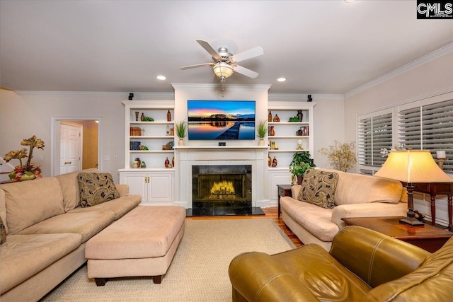 living room featuring light wood-type flooring, ornamental molding, built in features, ceiling fan, and a premium fireplace