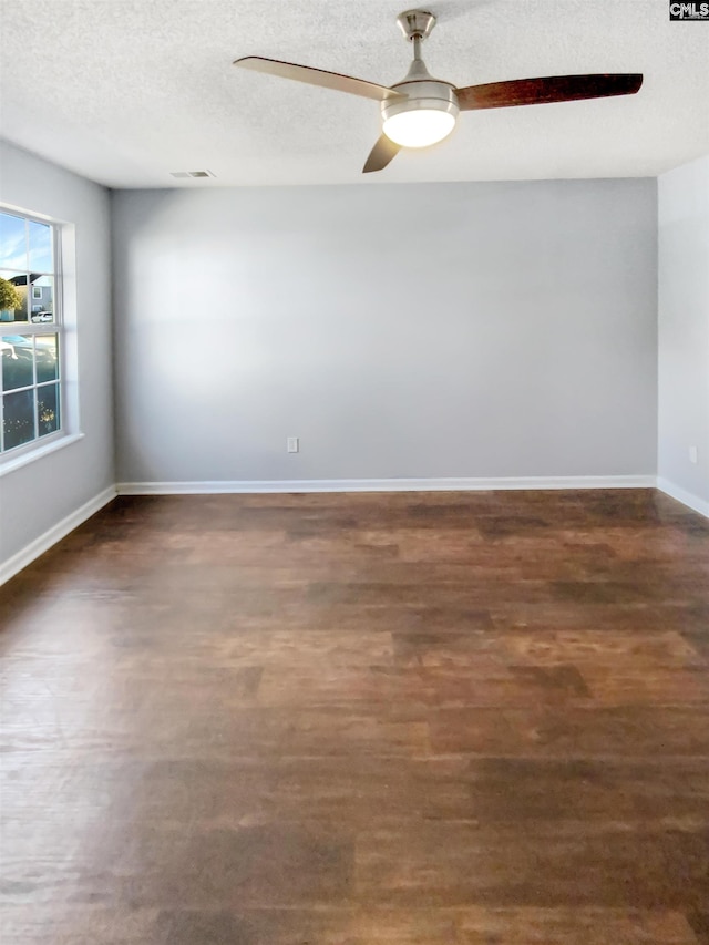 empty room with dark hardwood / wood-style flooring and a textured ceiling