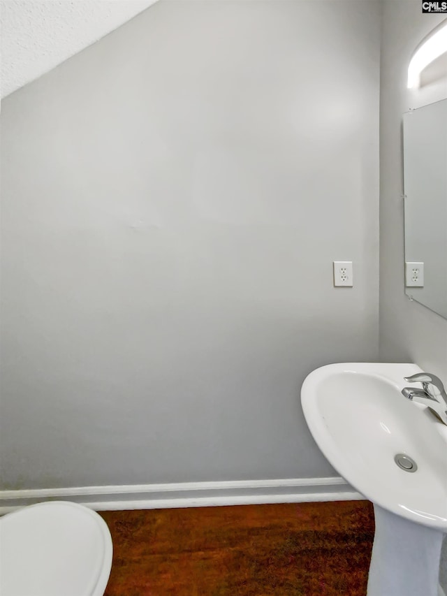 bathroom featuring sink, vaulted ceiling, and toilet