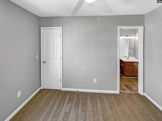 unfurnished bedroom with ensuite bath, ceiling fan, sink, and a textured ceiling