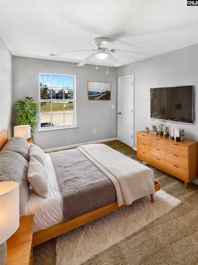 carpeted bedroom featuring ceiling fan and a textured ceiling