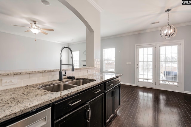 kitchen featuring sink, dark wood-type flooring, tasteful backsplash, light stone counters, and pendant lighting