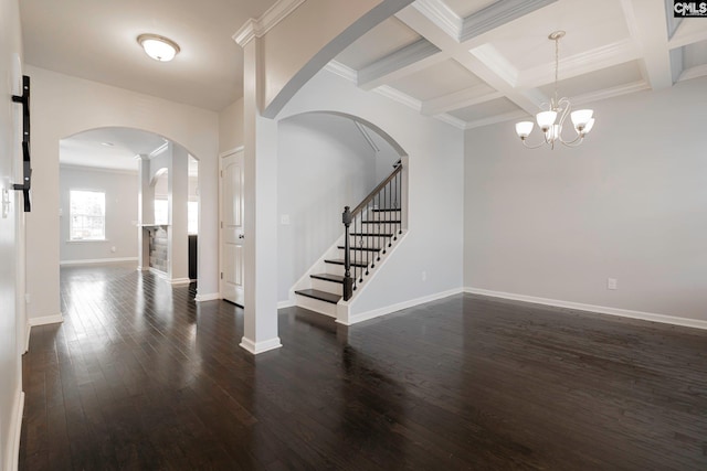 spare room with coffered ceiling, dark hardwood / wood-style flooring, beamed ceiling, a notable chandelier, and crown molding