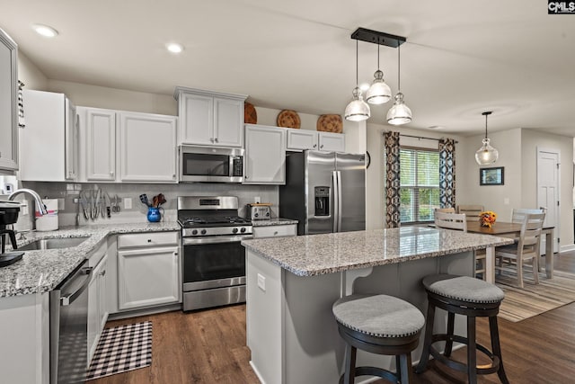 kitchen with dark wood-type flooring, white cabinets, sink, appliances with stainless steel finishes, and a kitchen island