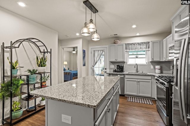 kitchen with ceiling fan, sink, stainless steel appliances, dark hardwood / wood-style floors, and a kitchen island