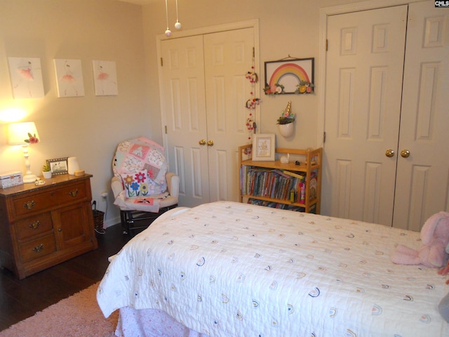 bedroom with dark hardwood / wood-style flooring and multiple closets