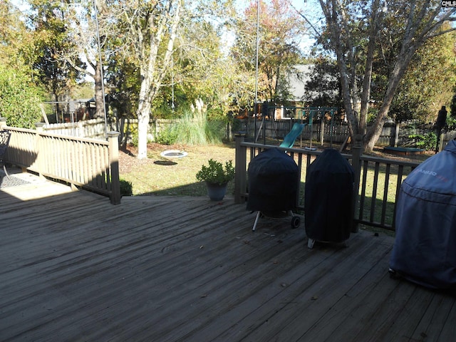 wooden deck with a playground and a grill