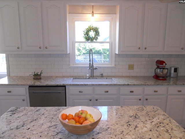 kitchen with dishwasher, light stone counters, white cabinetry, and sink