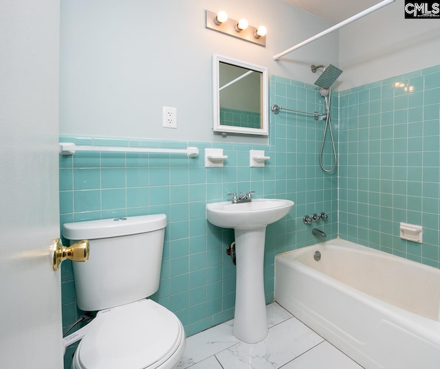 bathroom with tiled shower / bath combo, toilet, and tile walls