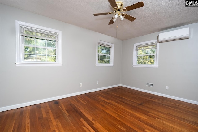 empty room with hardwood / wood-style floors, plenty of natural light, and a wall mounted air conditioner