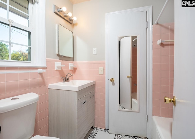 bathroom featuring tile patterned floors, vanity, toilet, and tile walls