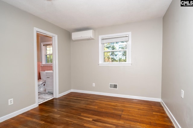 spare room with an AC wall unit and dark hardwood / wood-style flooring