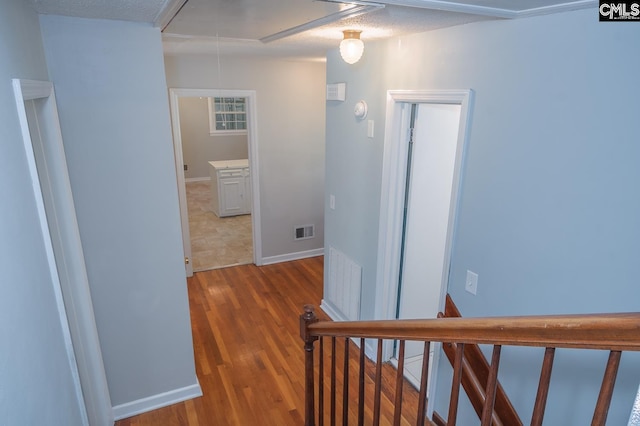 hall with hardwood / wood-style floors and a textured ceiling