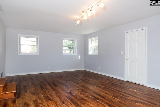 spare room with track lighting and dark wood-type flooring