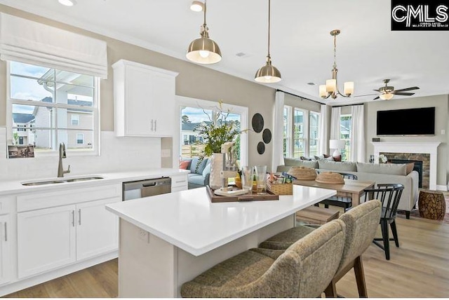 kitchen featuring white cabinets, a stone fireplace, a kitchen island, and sink