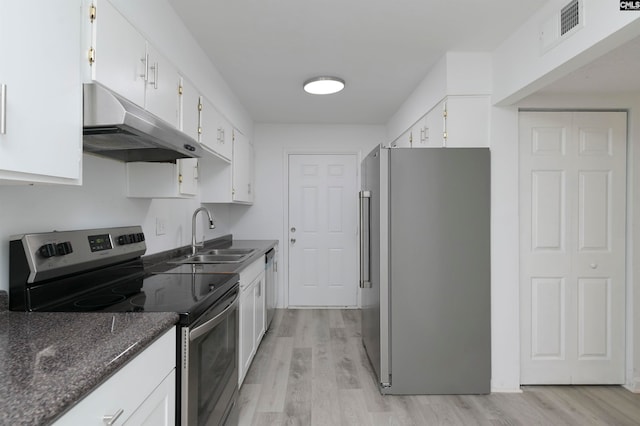 kitchen with sink, stainless steel appliances, dark stone counters, white cabinets, and light wood-type flooring