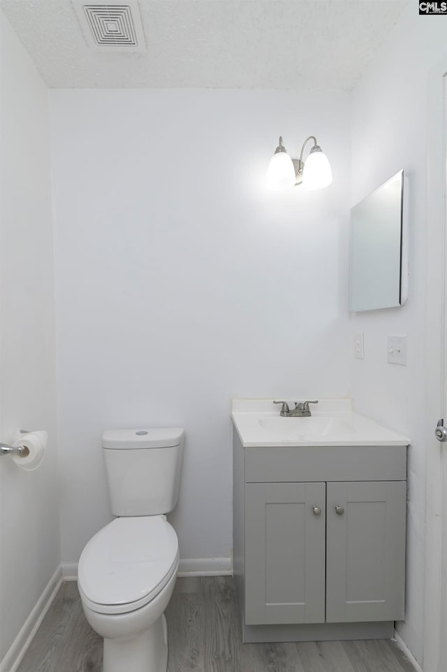 bathroom with hardwood / wood-style floors, vanity, a textured ceiling, and toilet