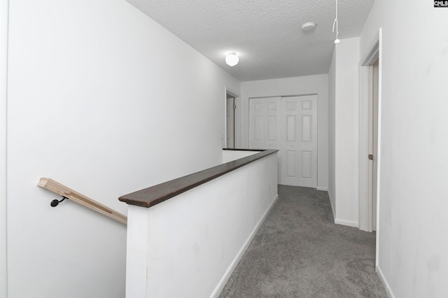 hallway featuring a textured ceiling and light carpet