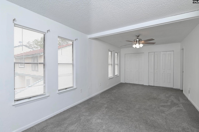 interior space with ceiling fan, dark carpet, and a textured ceiling