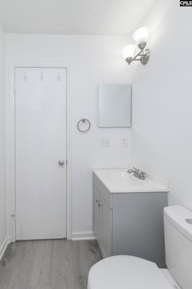 bathroom featuring vanity, toilet, wood-type flooring, and a textured ceiling