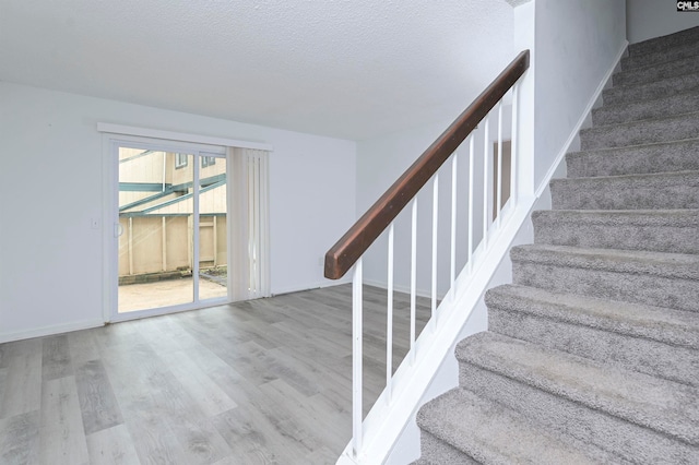 stairs with wood-type flooring and a textured ceiling