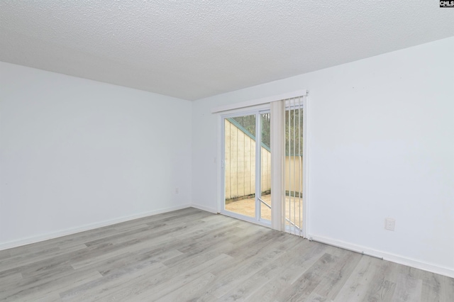 spare room with a textured ceiling and light wood-type flooring